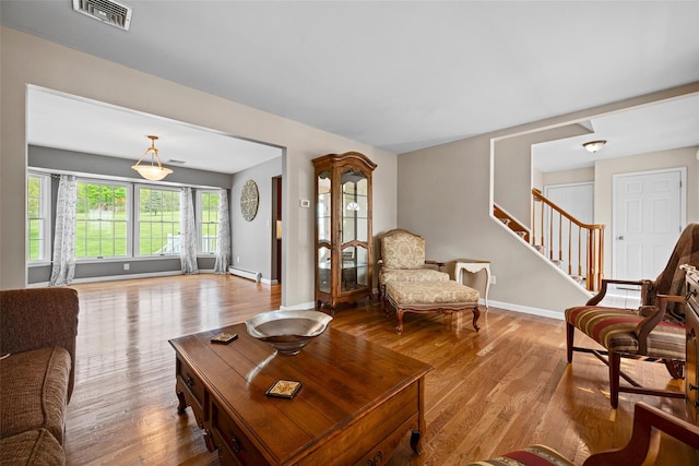 living area with visible vents, wood finished floors, stairway, baseboards, and a baseboard radiator