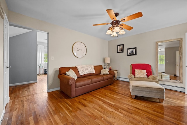 living area with light wood-style floors, a baseboard radiator, and a healthy amount of sunlight