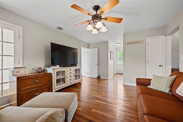 living room with ceiling fan, baseboards, wood finished floors, a baseboard radiator, and visible vents