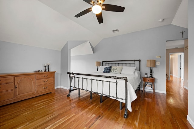 bedroom featuring ceiling fan, visible vents, wood finished floors, baseboards, and lofted ceiling