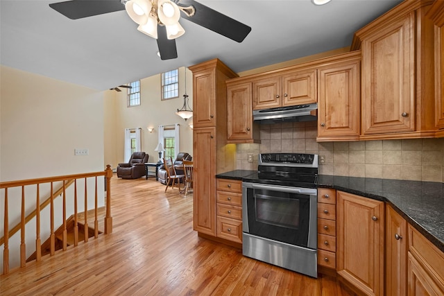 kitchen featuring light wood-style flooring, electric stove, a ceiling fan, decorative backsplash, and under cabinet range hood
