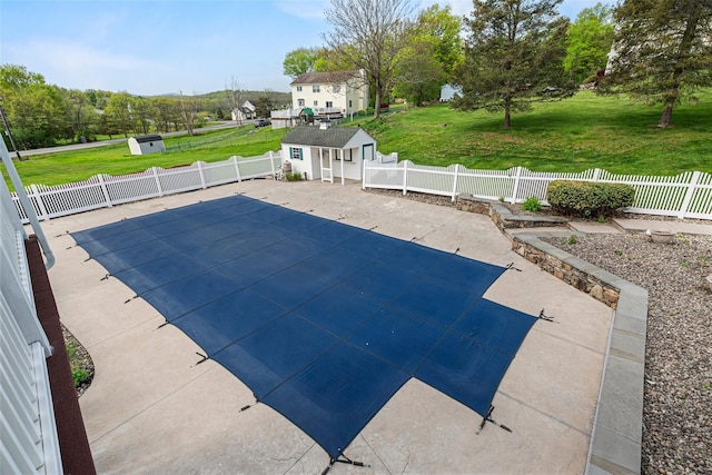 view of swimming pool with a yard, an outdoor structure, a fenced backyard, and a patio area