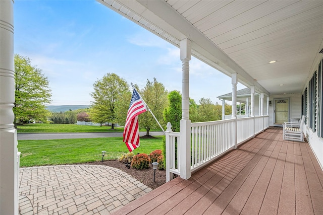 wooden terrace featuring a water view, a yard, and a porch
