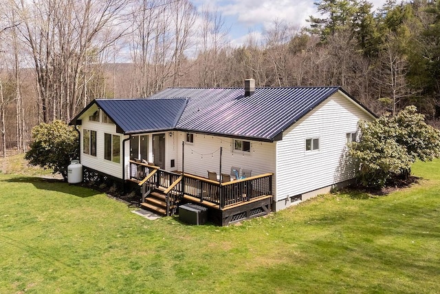 rear view of property with metal roof, a lawn, a deck, and a chimney