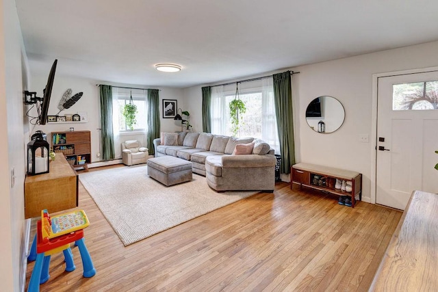 living room with baseboard heating, a healthy amount of sunlight, and light wood-style flooring