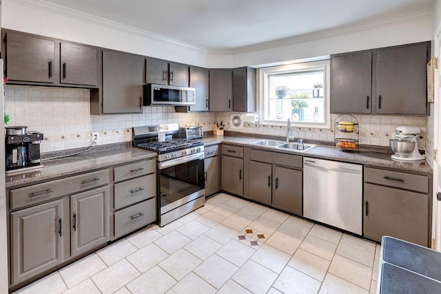 kitchen with dark countertops, a sink, backsplash, and appliances with stainless steel finishes