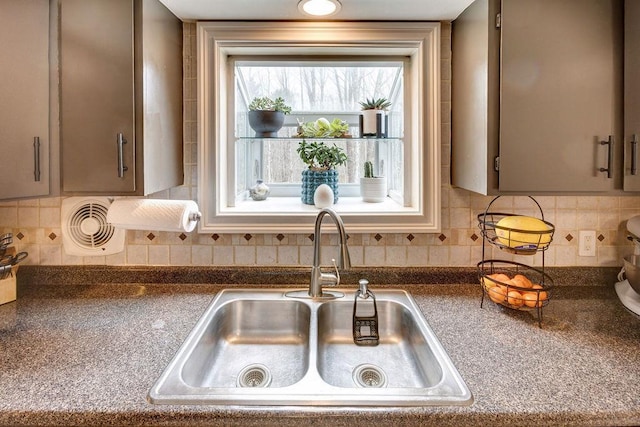 interior details featuring dark countertops, tasteful backsplash, gray cabinets, and a sink