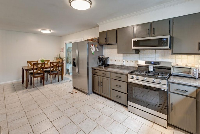 kitchen featuring light tile patterned floors, tasteful backsplash, crown molding, stainless steel appliances, and a toaster
