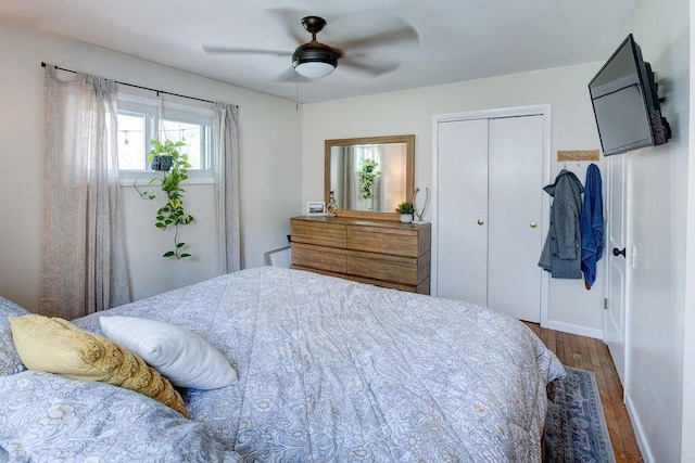 bedroom with wood finished floors, ceiling fan, baseboards, and a closet