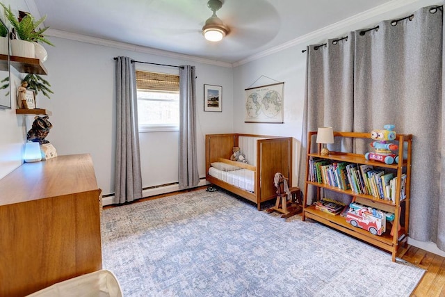 sitting room with ornamental molding, a ceiling fan, and wood finished floors