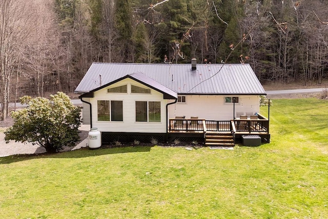 rear view of house featuring metal roof, a deck, a yard, and a wooded view