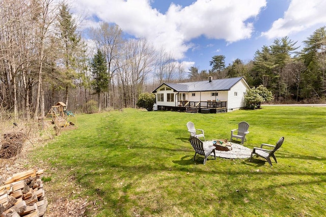 view of yard featuring a fire pit, a wooden deck, and a playground