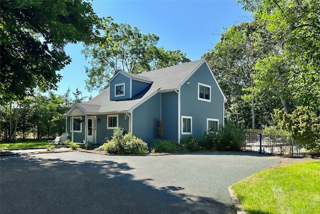 view of front of property with fence, driveway, and roof with shingles