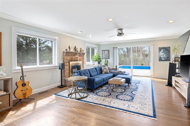 living room featuring wood finished floors, visible vents, plenty of natural light, and ornamental molding
