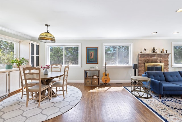 dining space with hardwood / wood-style floors, plenty of natural light, baseboards, and a brick fireplace
