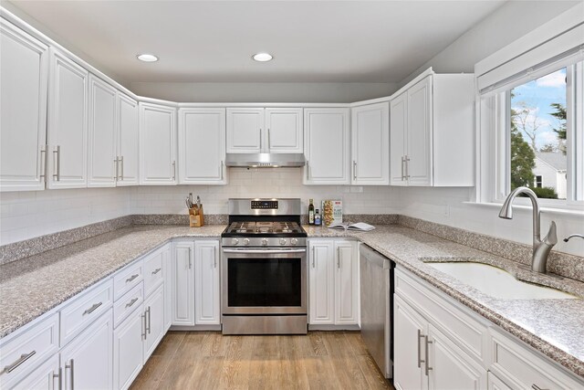 kitchen featuring a sink, stainless steel appliances, white cabinets, and under cabinet range hood
