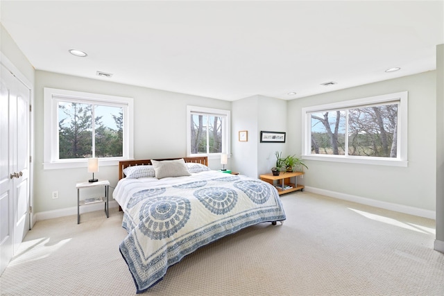 bedroom featuring visible vents, multiple windows, light colored carpet, and baseboards