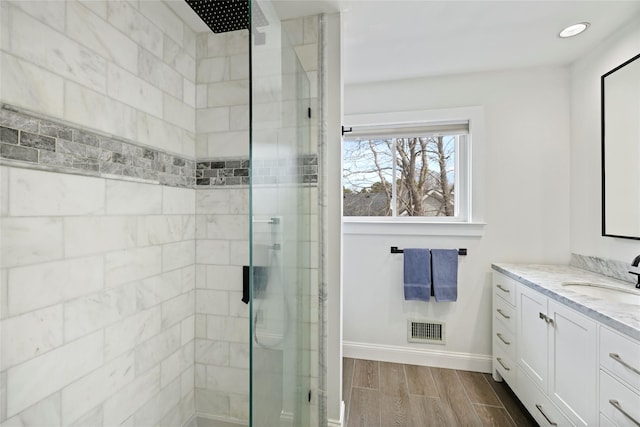 bathroom featuring vanity, a stall shower, visible vents, baseboards, and wood finished floors