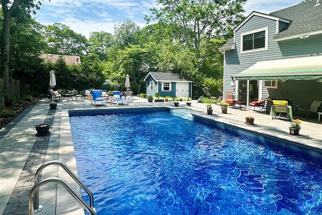 outdoor pool with a storage unit, an outbuilding, and a patio area