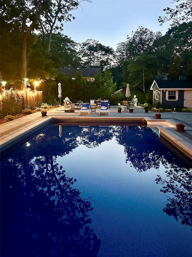 outdoor pool featuring a patio area and an outbuilding