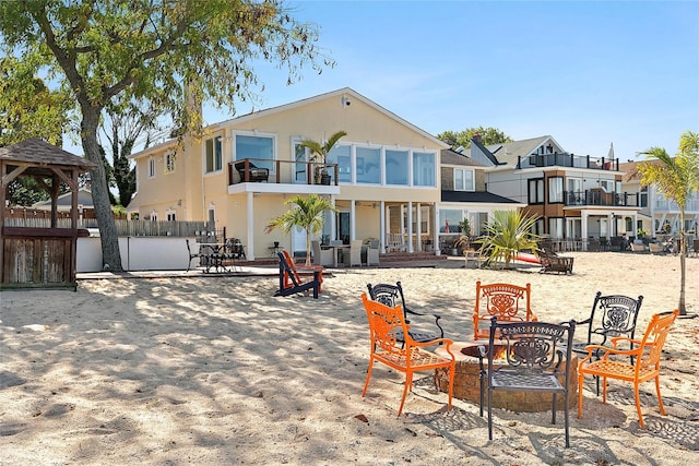 back of house featuring a balcony, a residential view, a gazebo, a fire pit, and fence