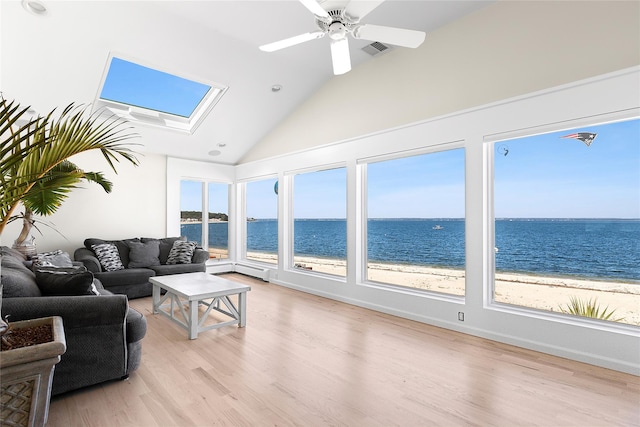 living room with visible vents, a skylight, a water view, and light wood finished floors
