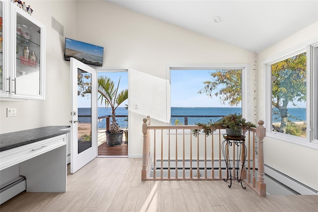 interior space with light wood finished floors, a water view, vaulted ceiling, and a baseboard radiator