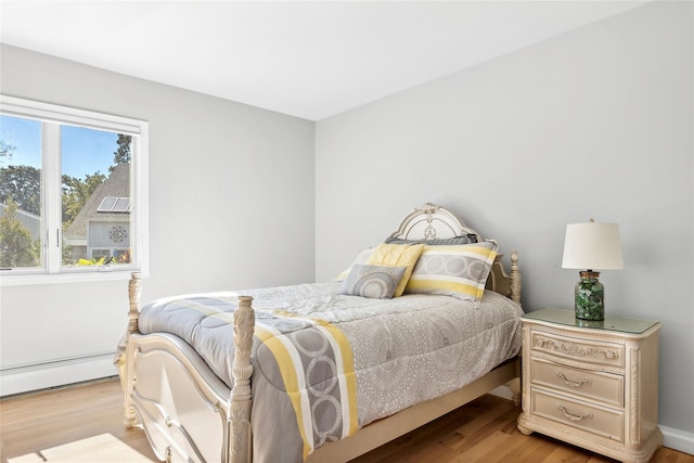 bedroom with wood finished floors and a baseboard radiator