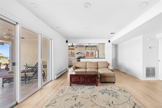 living area with light wood finished floors, a ceiling fan, visible vents, and baseboard heating