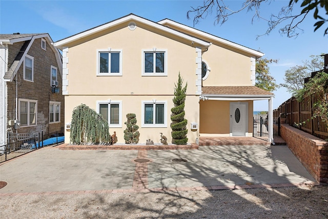 rear view of property featuring stucco siding, fence, and a patio