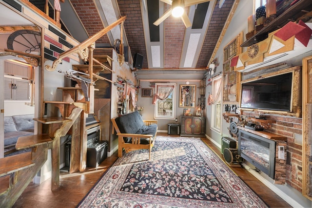 living room with a high ceiling, hardwood / wood-style floors, ceiling fan, stairs, and baseboards