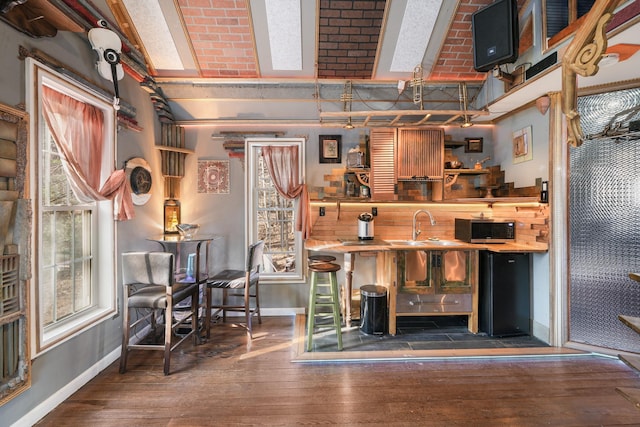 bar featuring baseboards, a sink, and hardwood / wood-style floors