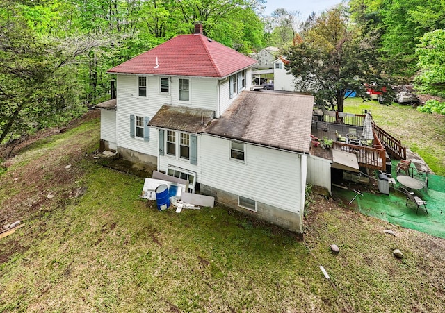 back of house with a chimney, a deck, a yard, and roof with shingles
