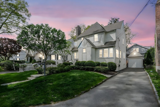 view of front of house with a chimney, a lawn, a garage, aphalt driveway, and stucco siding