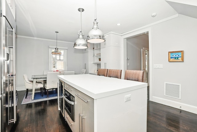 kitchen featuring appliances with stainless steel finishes, visible vents, dark wood-style floors, and a center island