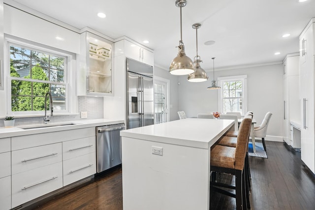 kitchen with a breakfast bar, light countertops, white cabinetry, a sink, and stainless steel appliances