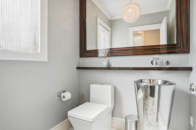 half bathroom featuring crown molding, baseboards, and toilet