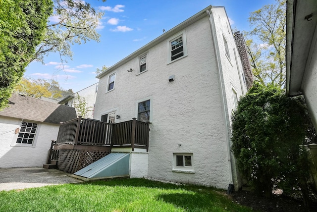 back of property with a lawn, stucco siding, and a deck