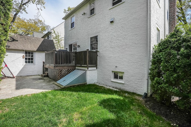 back of property with a yard, a deck, and stucco siding