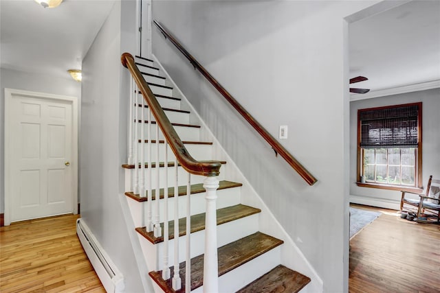 staircase featuring baseboard heating, wood finished floors, and baseboards