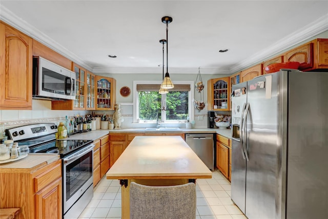 kitchen featuring appliances with stainless steel finishes, a sink, a kitchen island, backsplash, and glass insert cabinets