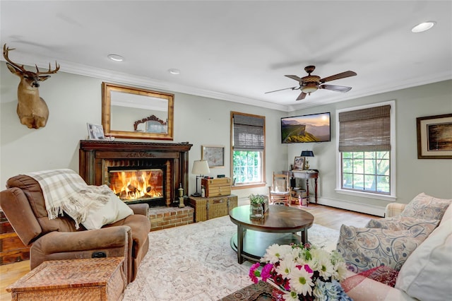 living area featuring crown molding, a fireplace, wood finished floors, recessed lighting, and a ceiling fan