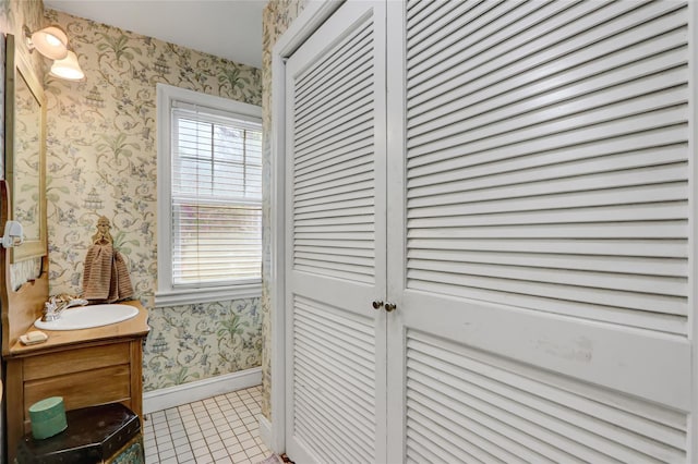 bathroom with wallpapered walls, tile patterned floors, plenty of natural light, vanity, and baseboards