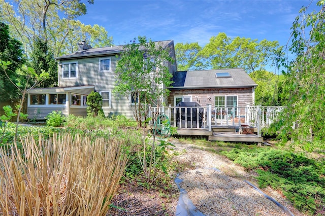 back of house with a chimney and a wooden deck