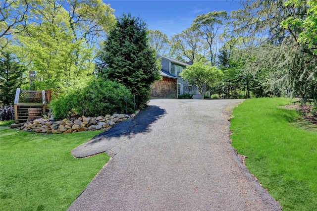 obstructed view of property featuring a front lawn, asphalt driveway, and stairway