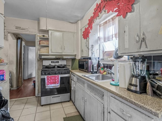 kitchen featuring light tile patterned floors, stainless steel appliances, open shelves, light countertops, and a sink