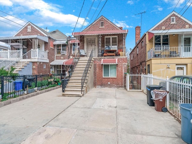 view of front of property with cooling unit, fence, stairway, and brick siding