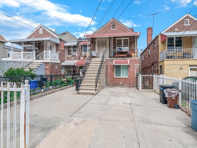 view of front of house with fence, stairs, and brick siding