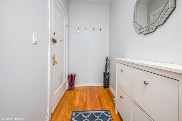 corridor featuring baseboards and light wood finished floors