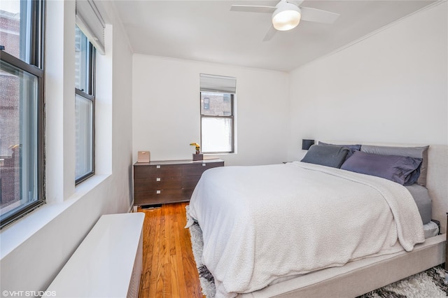 bedroom featuring crown molding, a ceiling fan, and wood finished floors